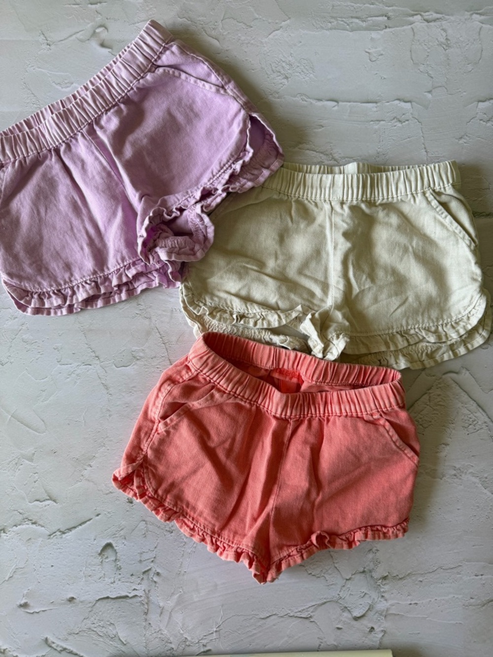 set of  girls’ ruffled hem cotton/linen shorts in lavender, khaki, and coral.